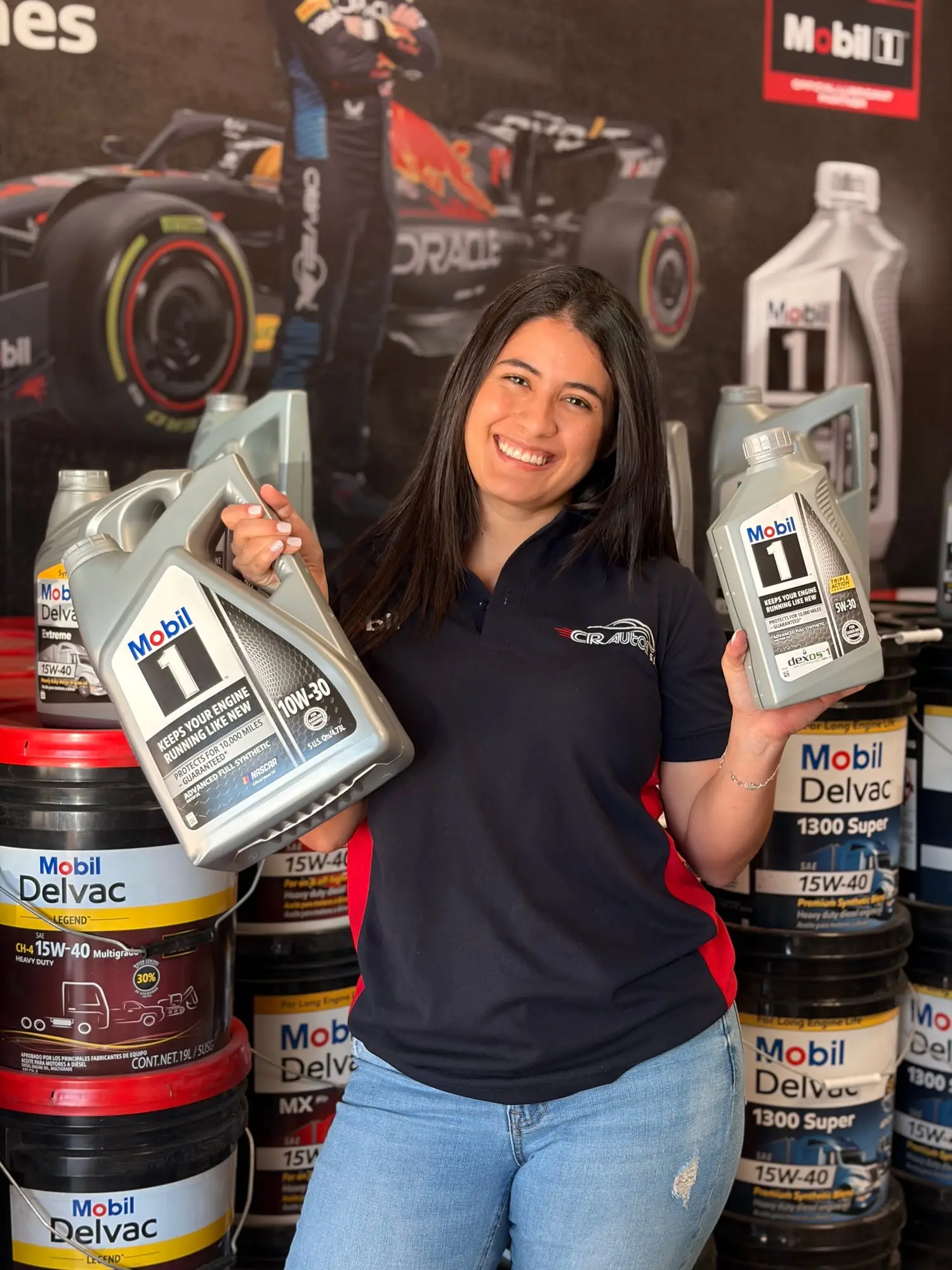 Asesora de CR Autos con dos envases de aceite Mobil 1 frente a cubetas de lubricante